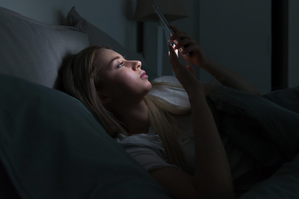Žena s mobilem v posteli